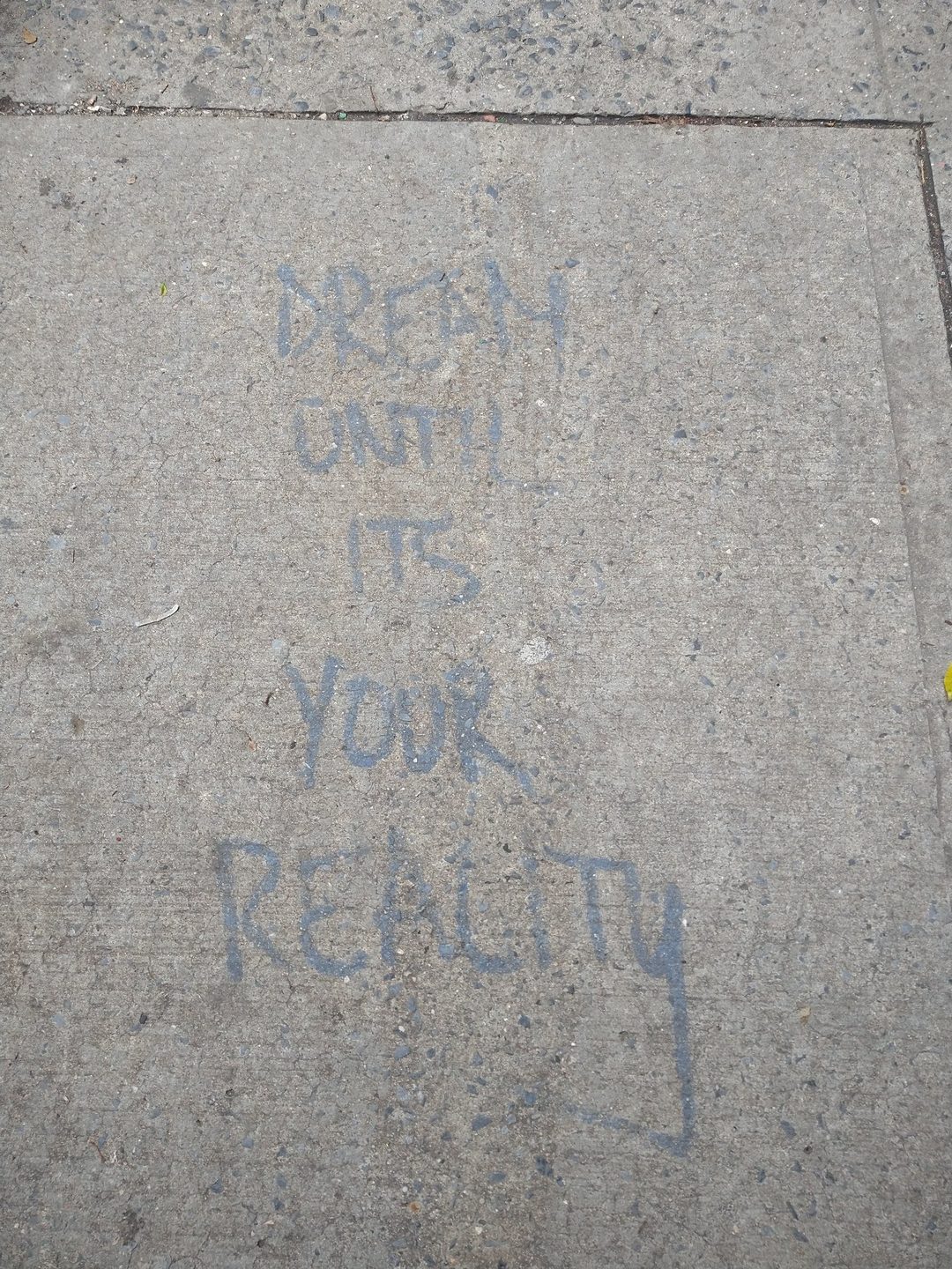 Sidewalk chalk writing that reads Dream until it's your reality